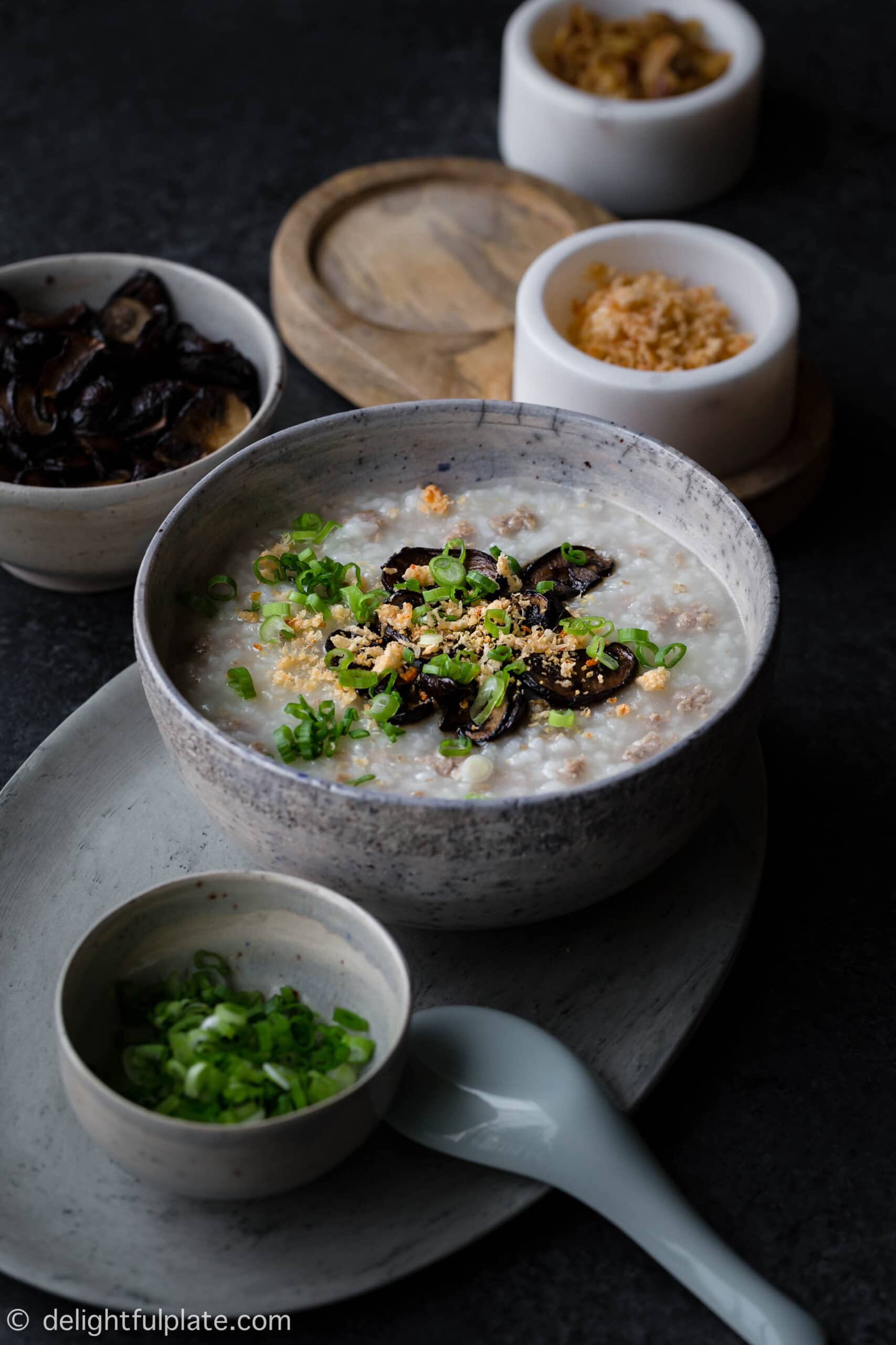 A Bowl of Congee with Ground Pork Topped with Mushrooms and Green Onions