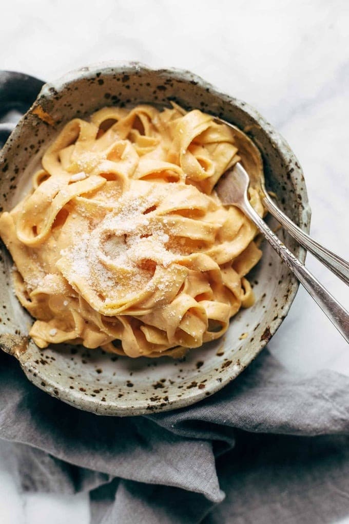 Pumpkin Alfredo pasta in a bowl garnished with parmesan cheese. 