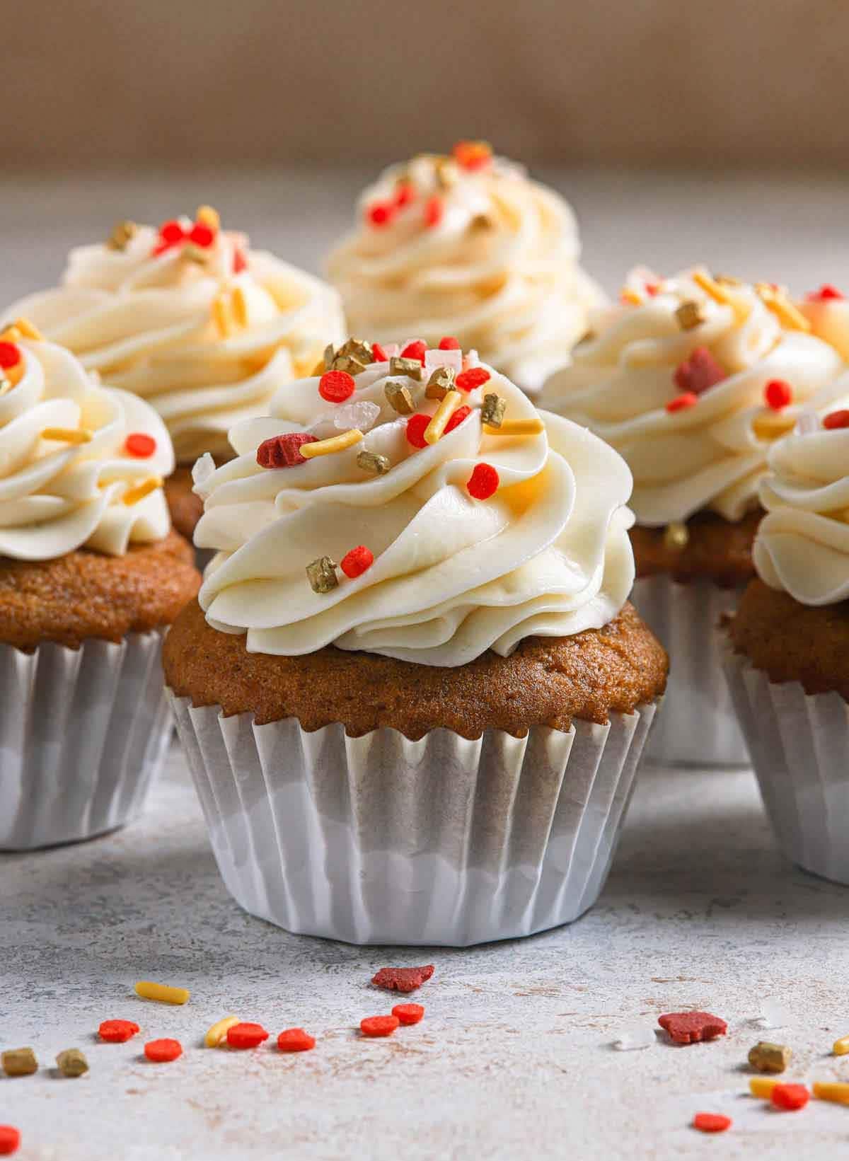 Pumpkin cupcakes with cream frosting on top.