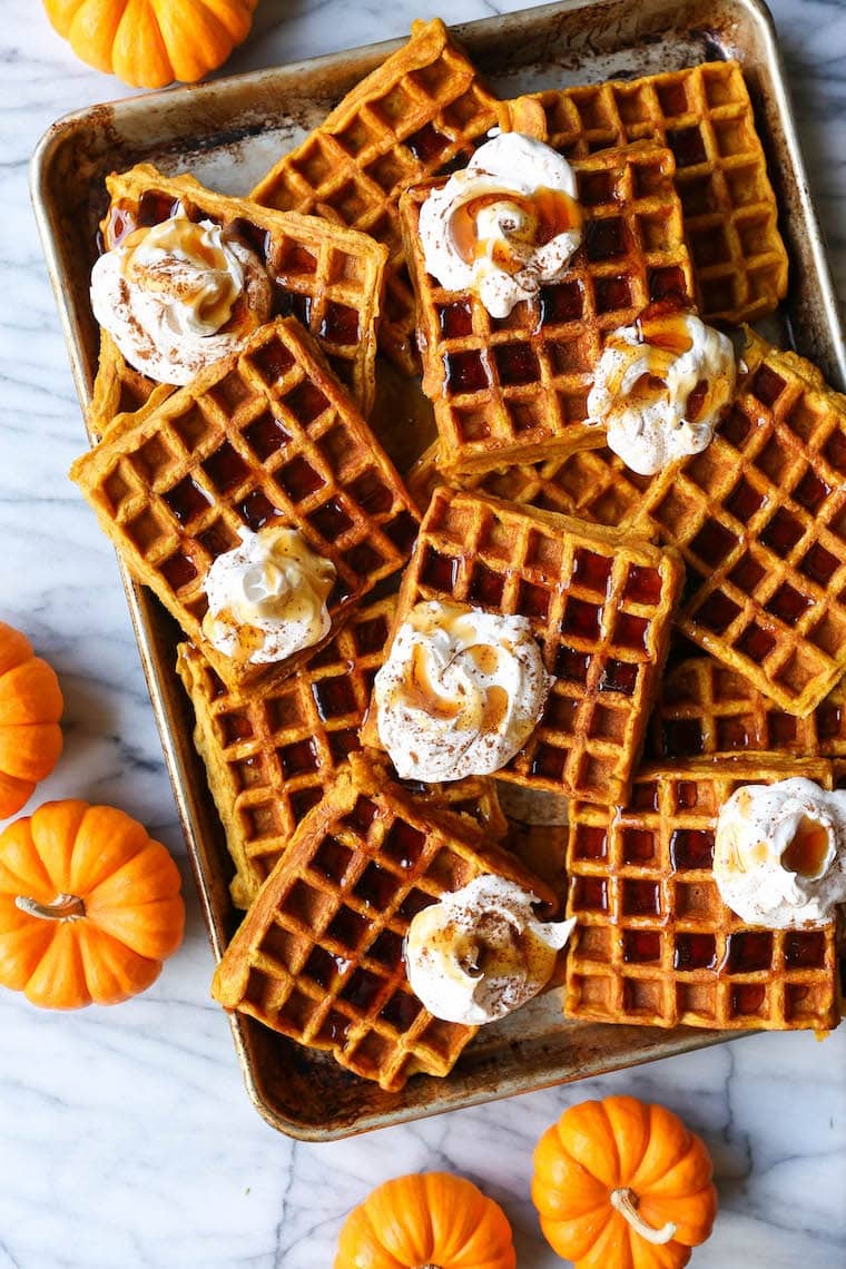 Pumpkin spice waffles on a sheet pan with maple syrup. 