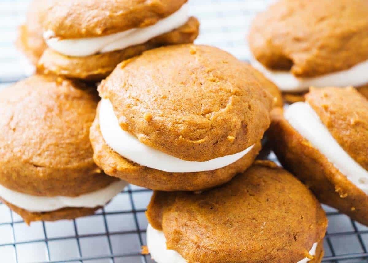 Bunch of pumpkin whoopie pies on a cooling rack. 