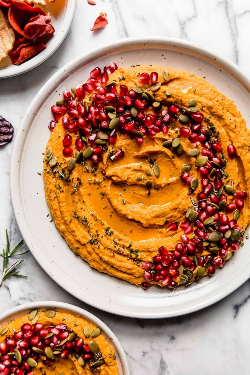 Creamy pumpkin hummus in a bowl with pomegranate arils. 