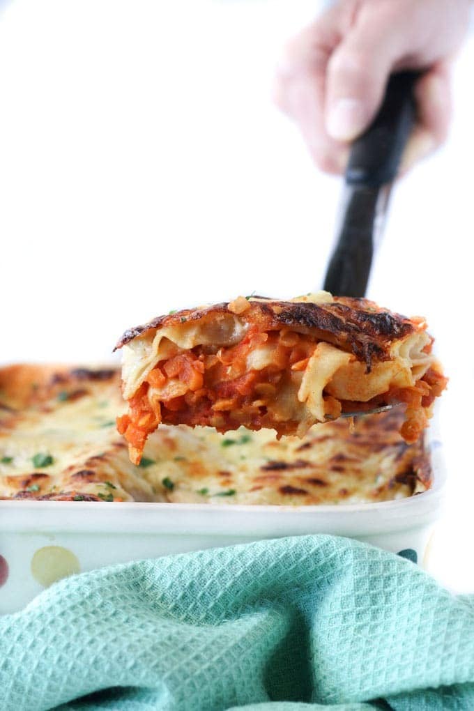 Red lentil lasagne with Layers of lentil with carrots, celery, garlic, and red bell pepper, with pasta sheets and a creamy cottage cheese and cheddar top.
