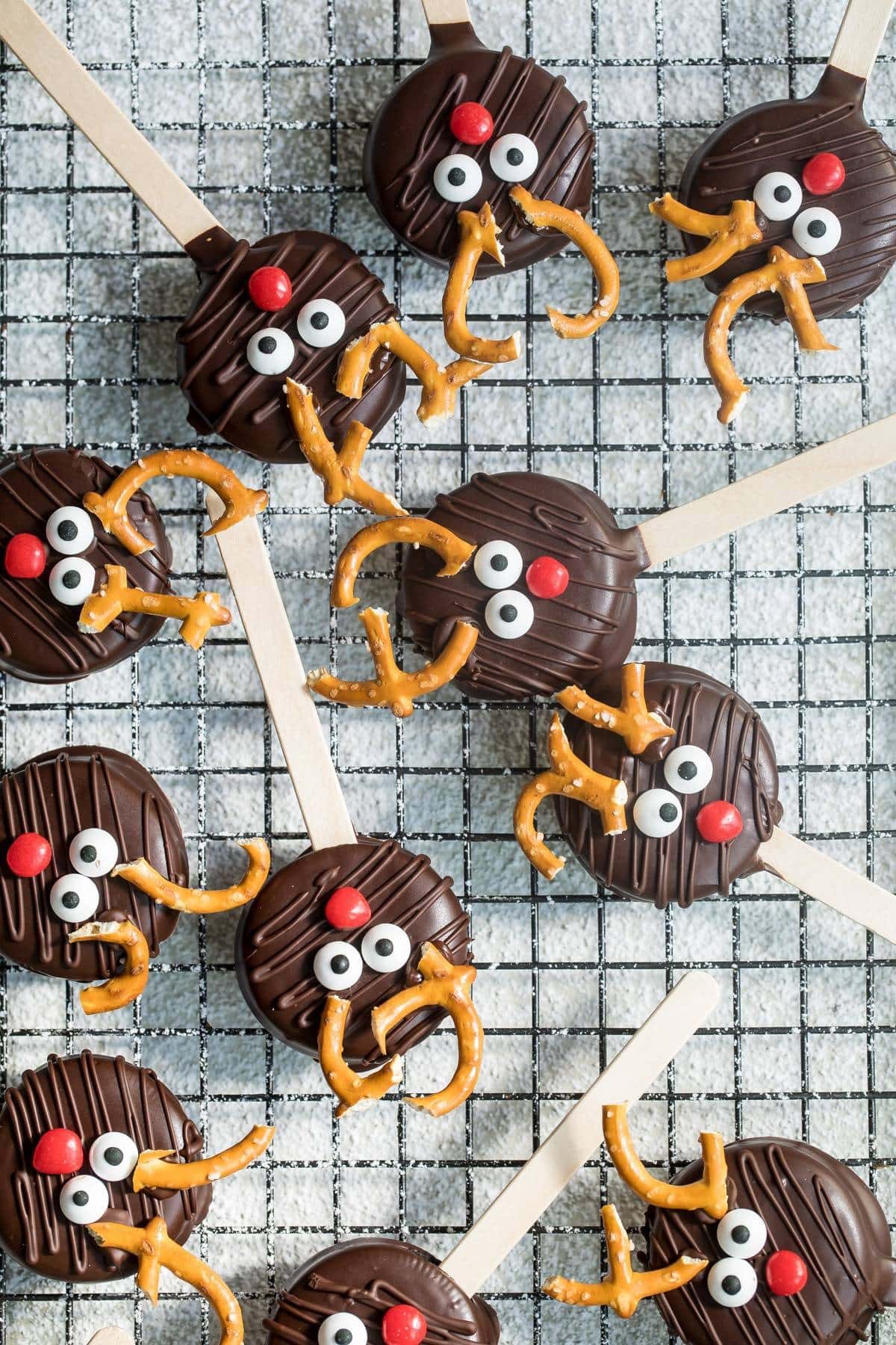 Chocolate reindeer cookie pops on a cooling rack. 