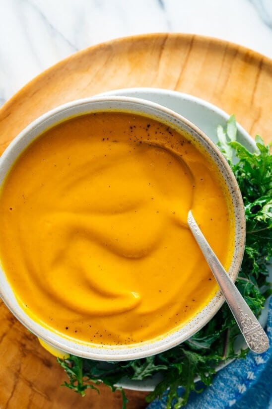 Bowl of homemade Roast Carrot Soup served with fresh arugula on the side