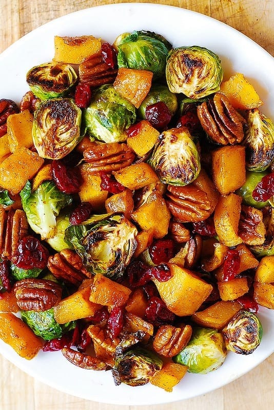 Roasted brussels sprouts and cinnamon butternut squash with pecans and cranberries on a plate. 