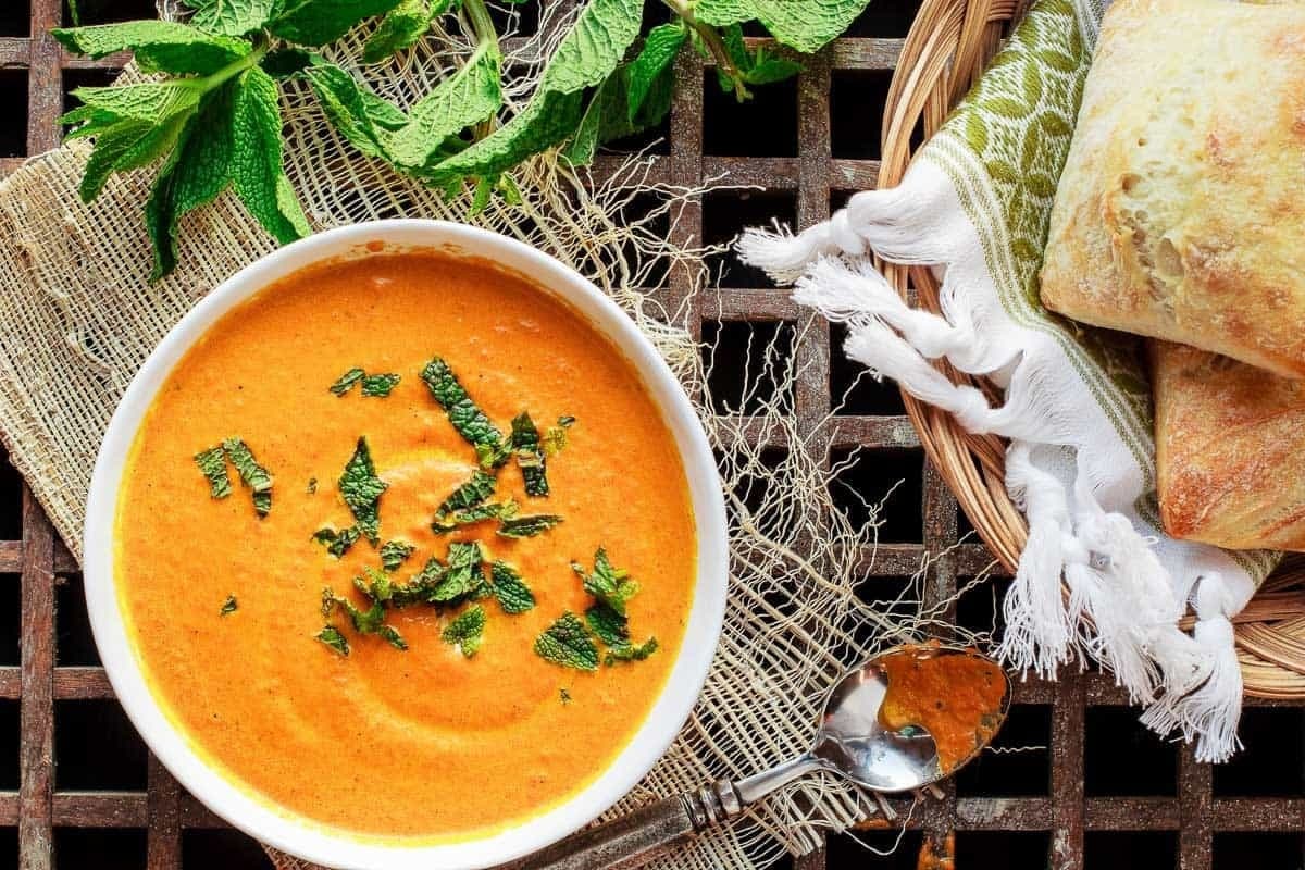 Bowl of Roasted Carrot Ginger Soup garnished with mint leaves