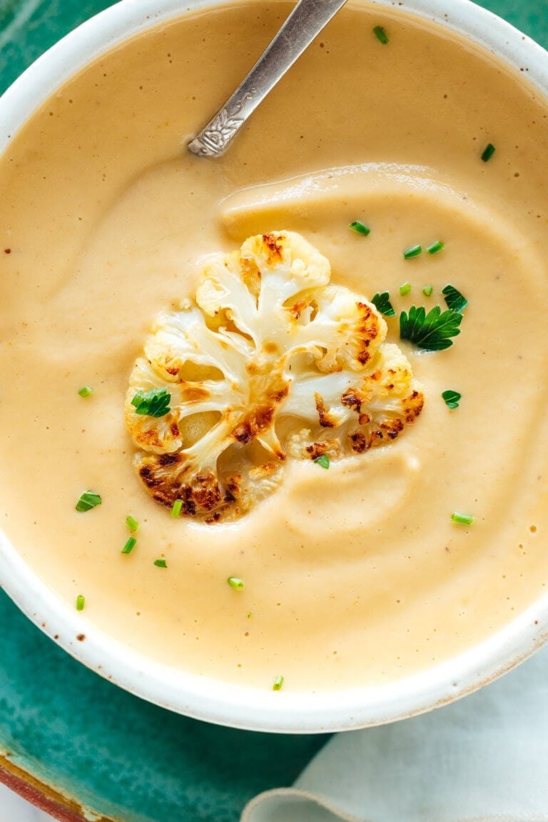 Top view of a Bowl of Roasted Cauliflower Soup garnished with chopped green onions and parsley