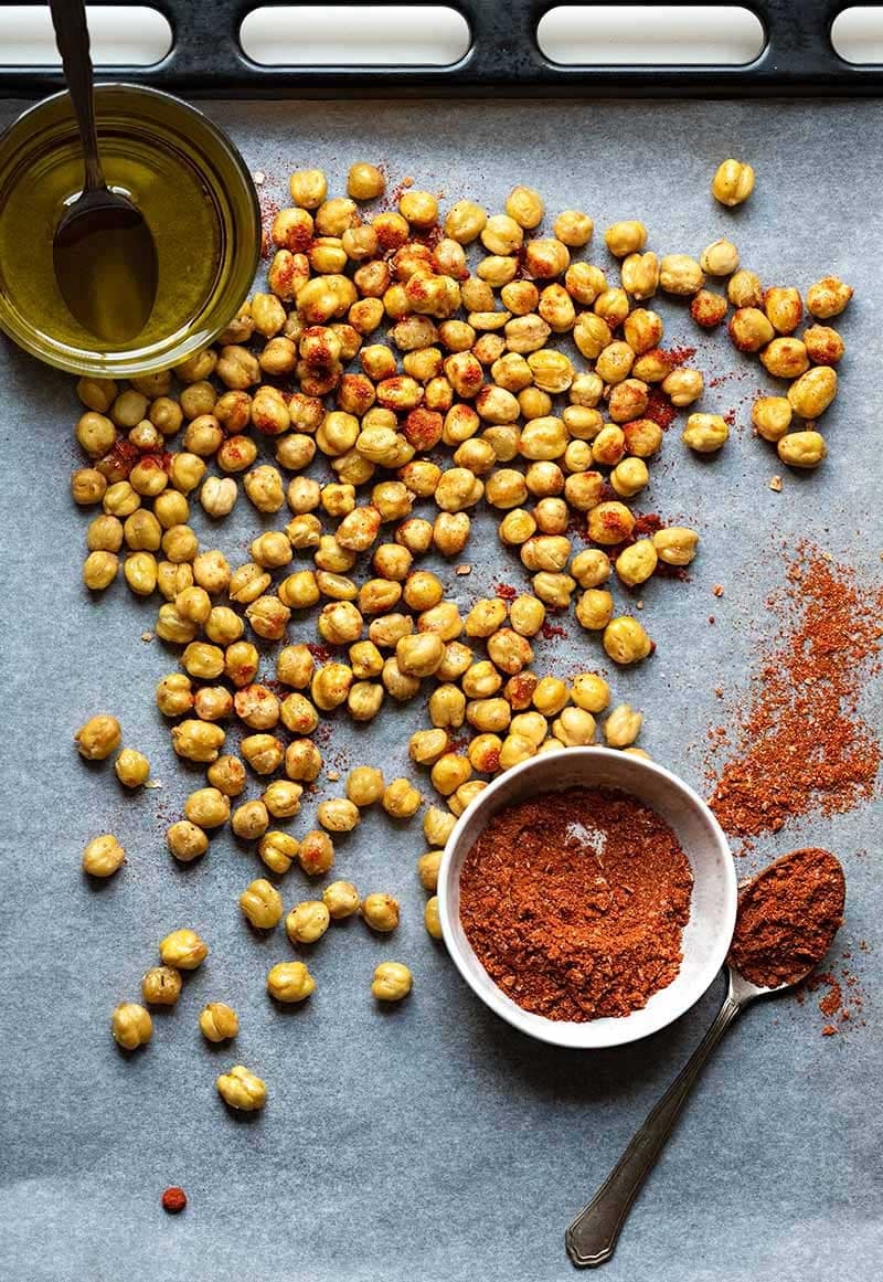 Roasted chickpeas on  concrete table with seasoning mixture on the side. 