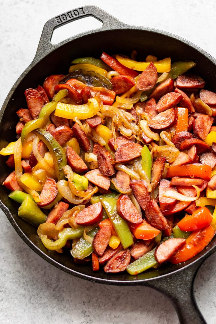 A skillet filled with sausage, peppers, and onions