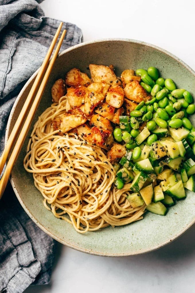Noodles served with beans, cucumber, chicken and sesame in a bowl. 