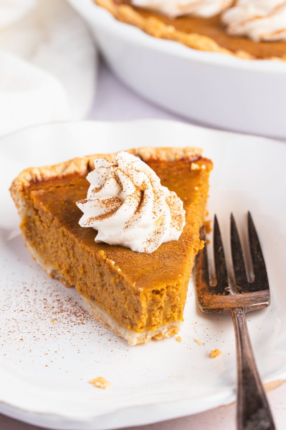 A slice of Libby's pumpkin pie with cream on top served on a white plate.