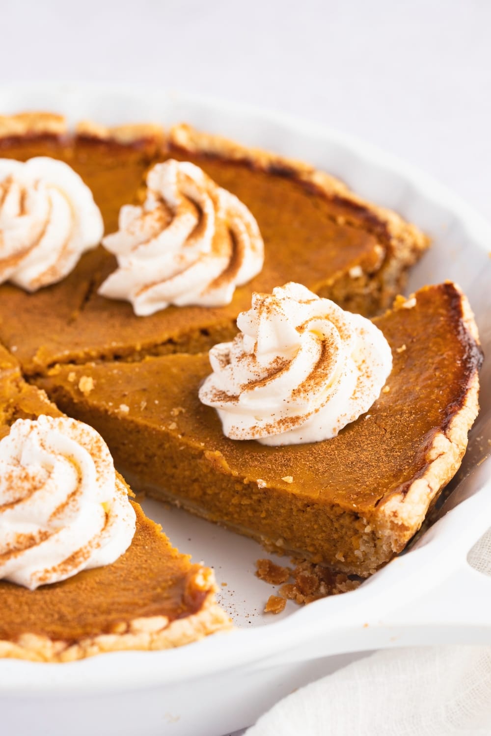 Sliced whole pumpkin pie with cream frosting on top. 
