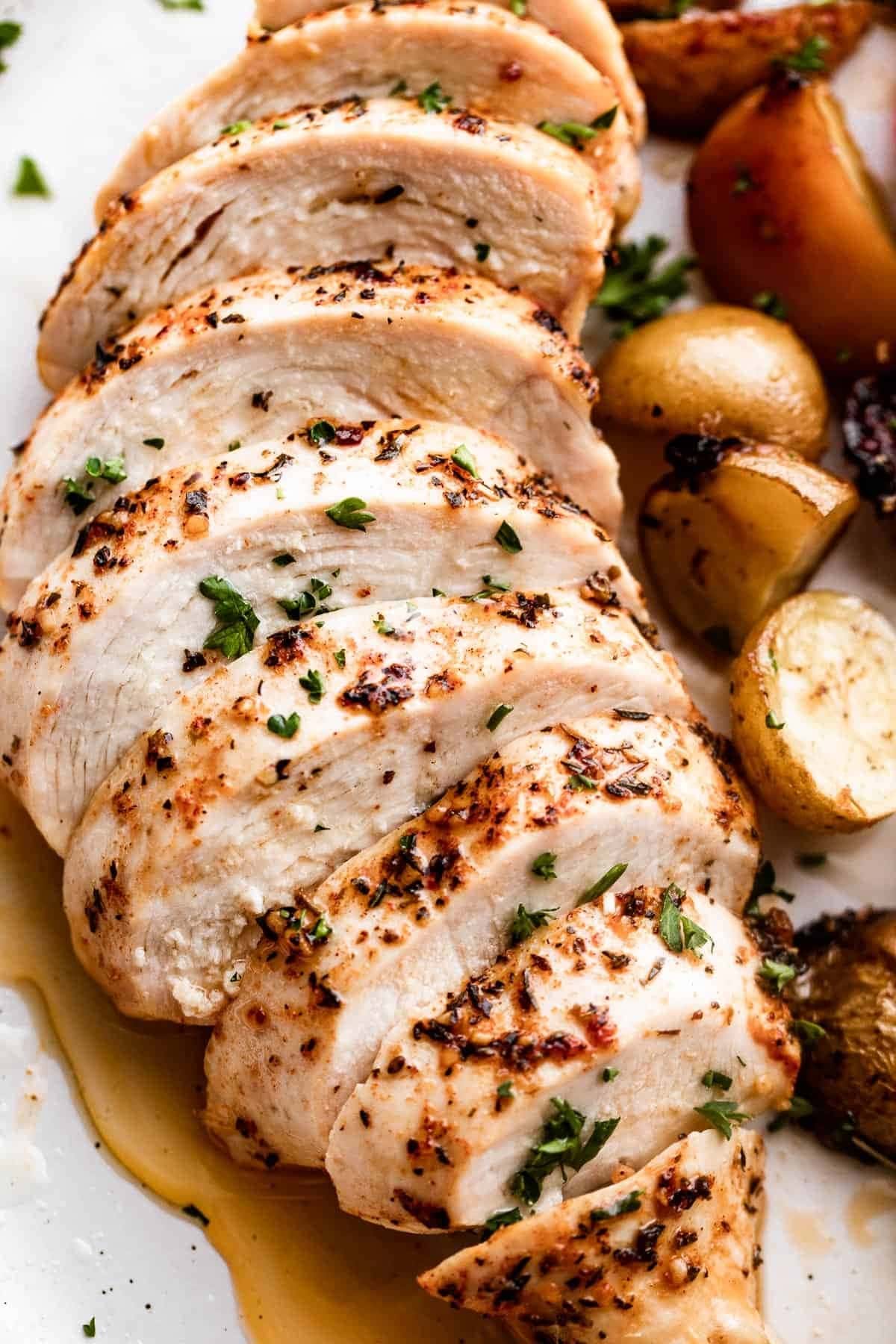 Sliced Slow Cooker Chicken Breasts served on a plate with roasted potatoes