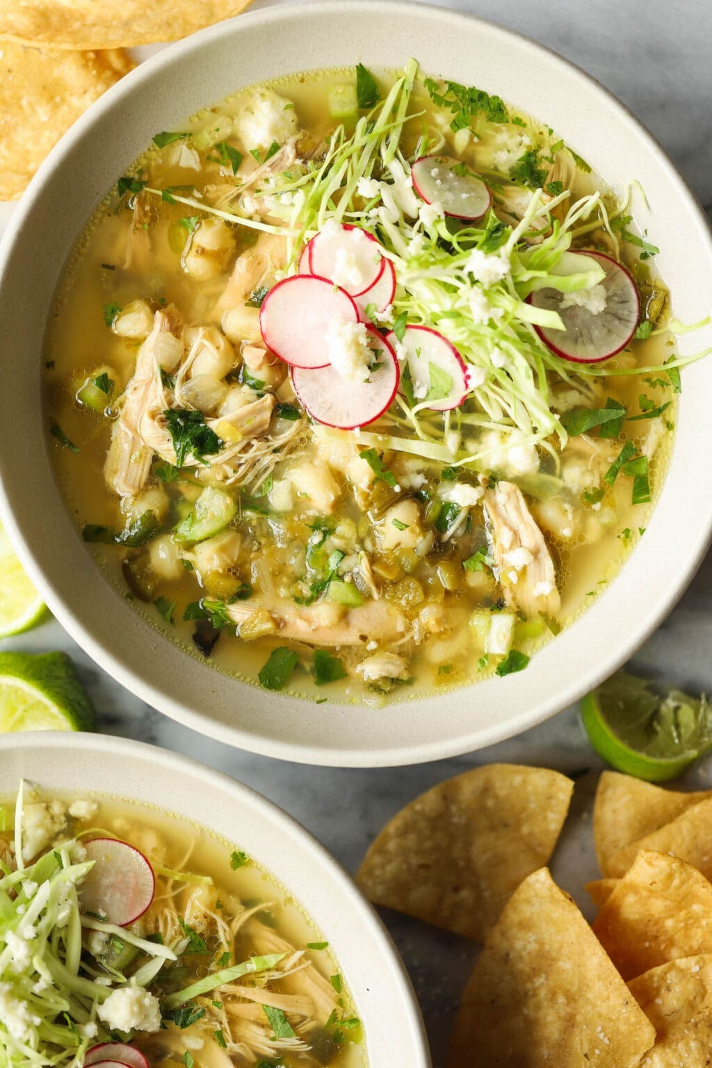 Bowl of homemade Slow Cooker Chicken Posole with nachos and slice lime on the side