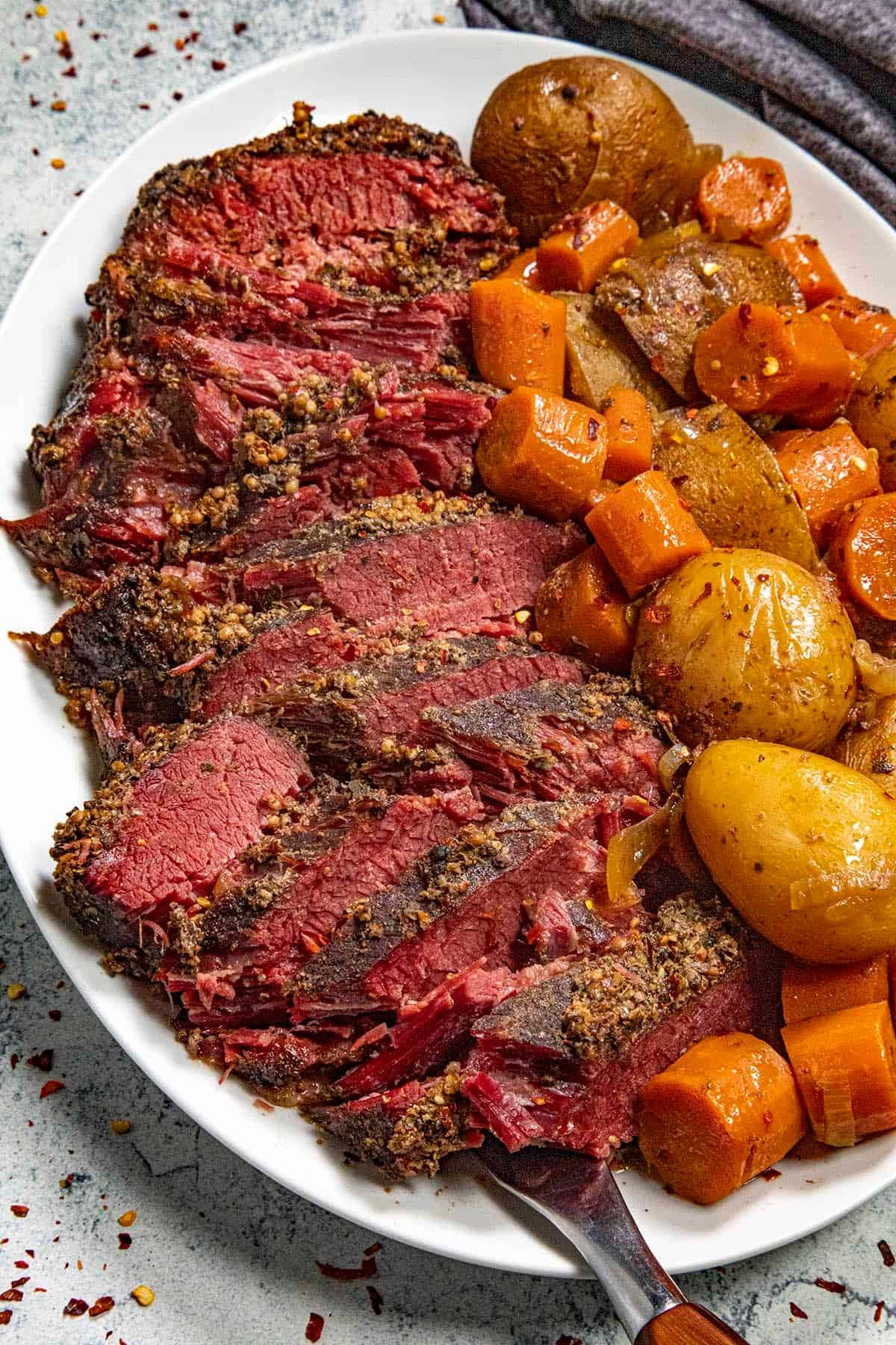 Slice Slow Cooker Corned Beef  with carrots and potatoes on the side