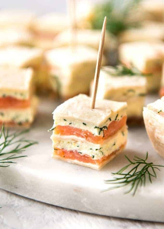 Flatbread with smoked salmon filling cut into square served with toothpicks.