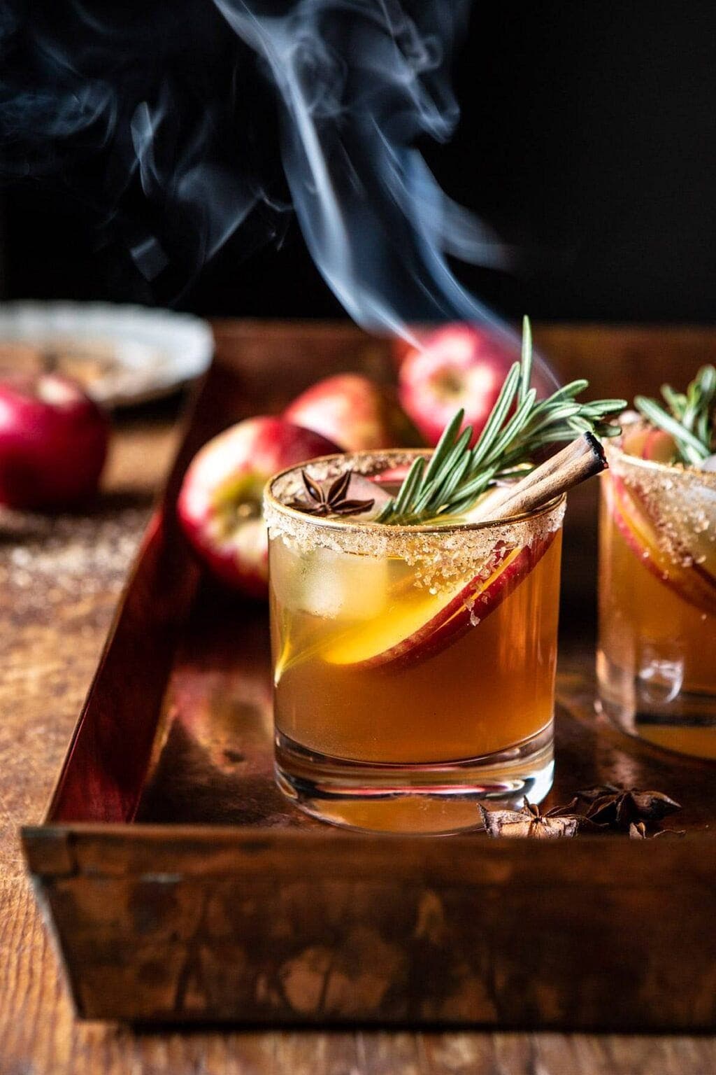 Glass of Smoky Apple Cider Margarita garnished with cinnamon sticks, sliced apple, star anise and rosemary