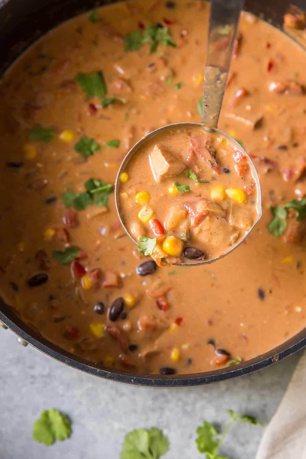 Creamy Southwest chicken soup in a pot scooped with a ladle. 