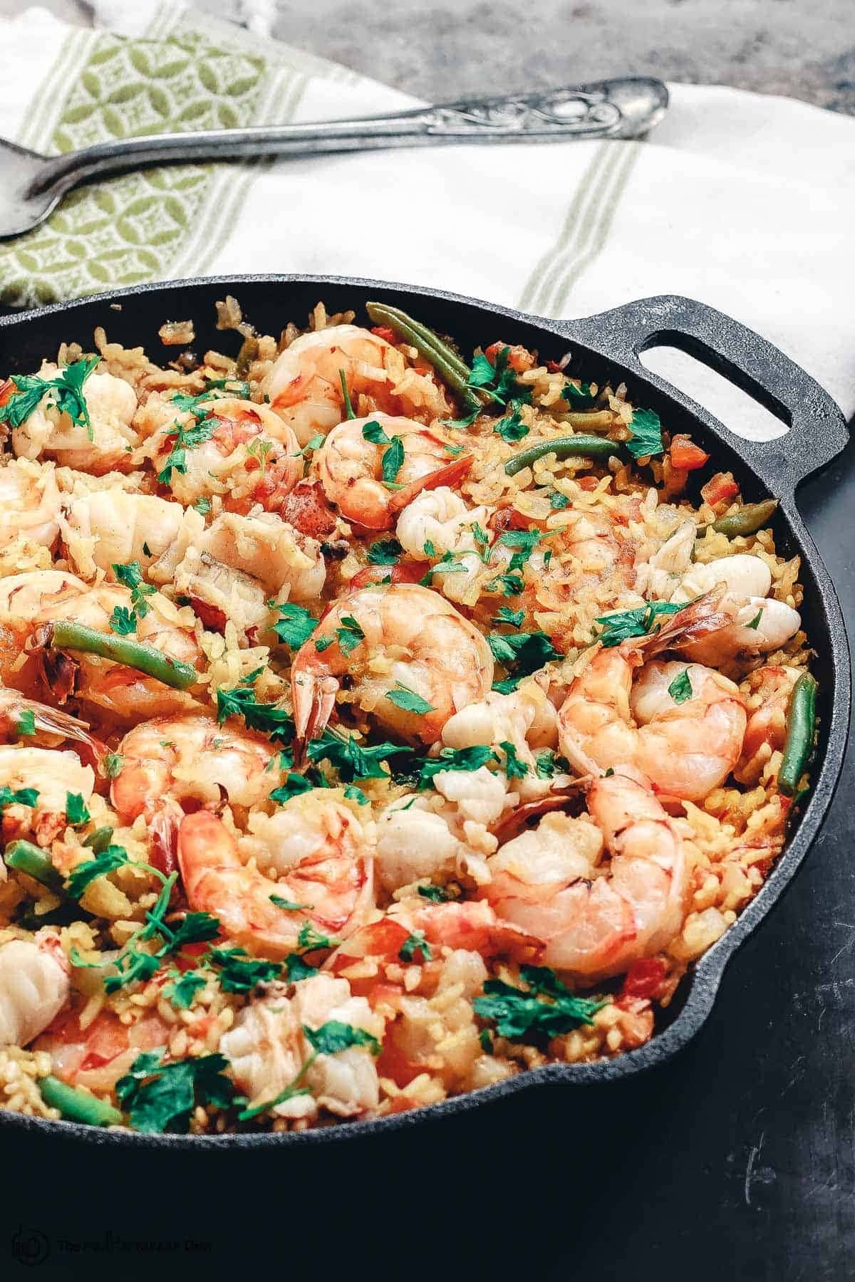Spanish seafood paella in a skillet with  rice, shrimp, vegetables, and saffron.