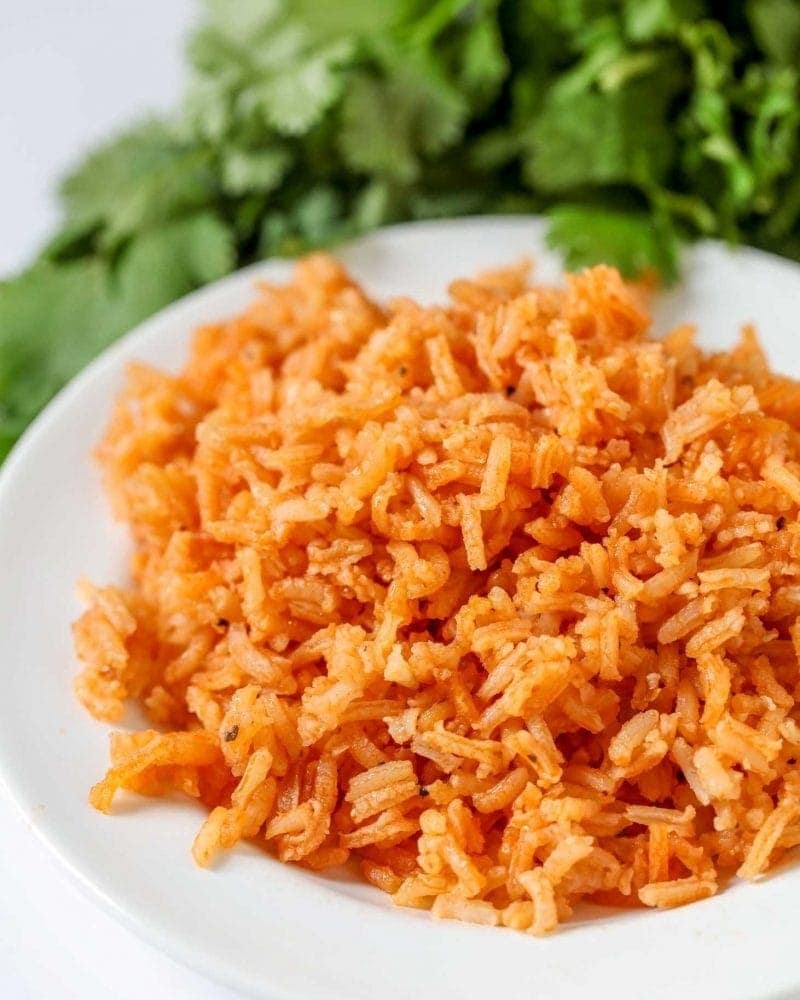 Spanish rice cooked in tomato sauce and broth served on a white plate. 