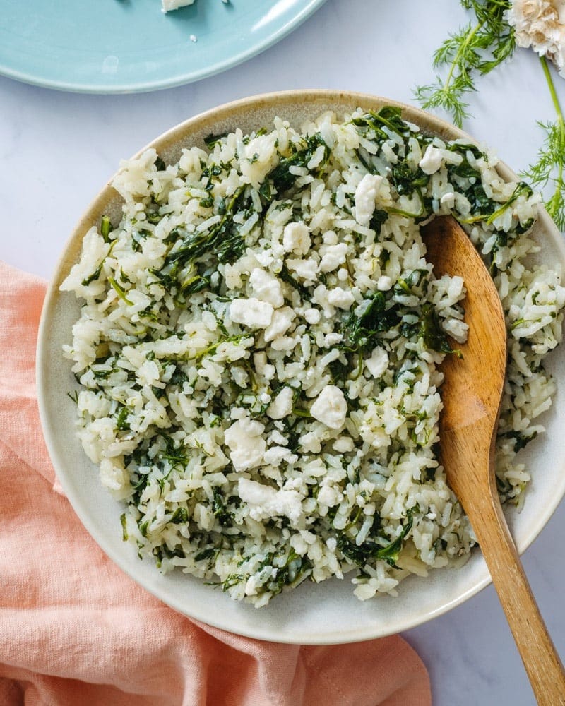 Rice in a plate mixed with spinach and feta cheese. 