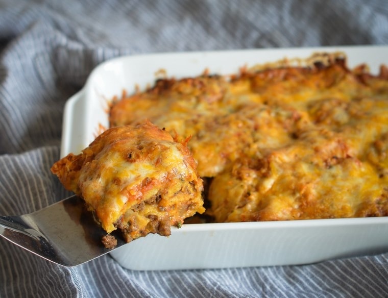Stacked beef enchiladas in a baking dish. 