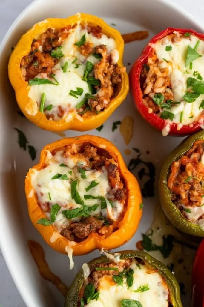 Stuffed bell peppers made with rice, ground beef with tomato sauce topped with melted cheese and parsley