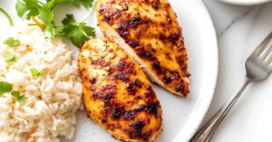Tender Homemade Chicken Breast with Rice on a White Plate