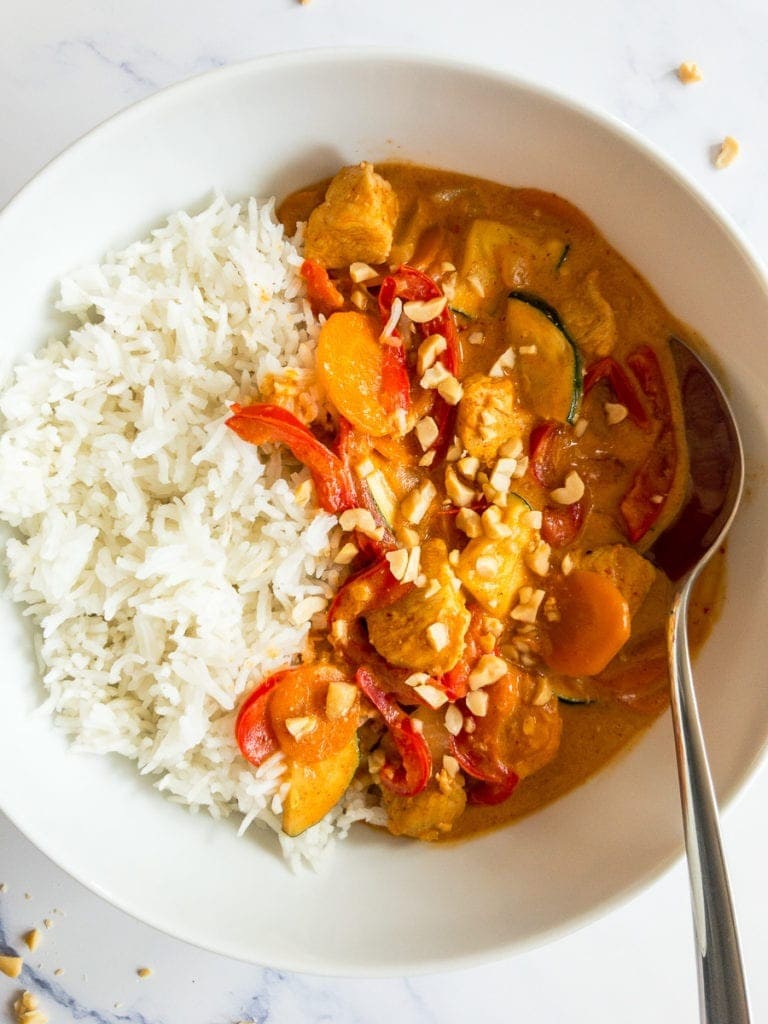 Thai peanut curry served with rice on a bowl with spoon. 