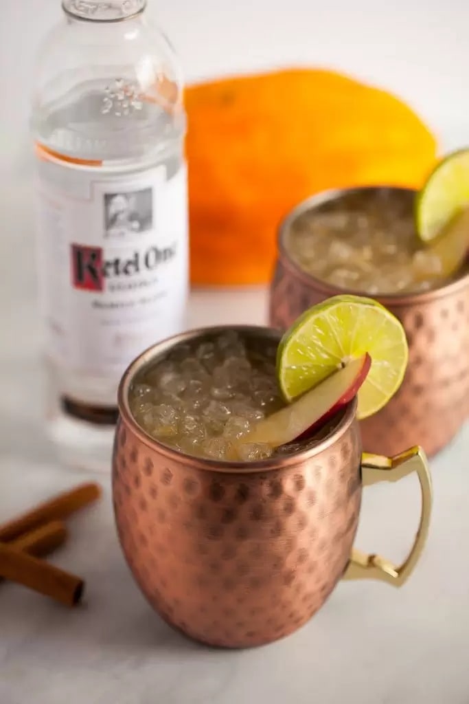 Pumpkin apple pie spice Moscow Mule filled with ice and garnished with apple and lemon slices. 