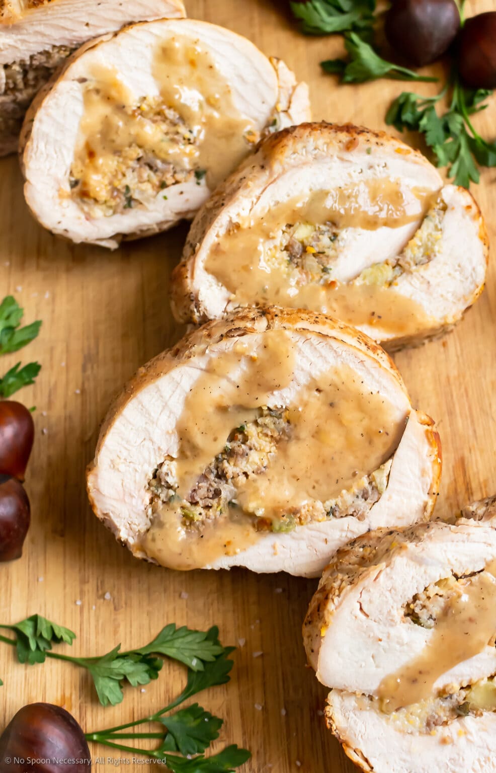 Thanksgiving Turkey Breast Roulade slices with sauce on a wooden cutting board