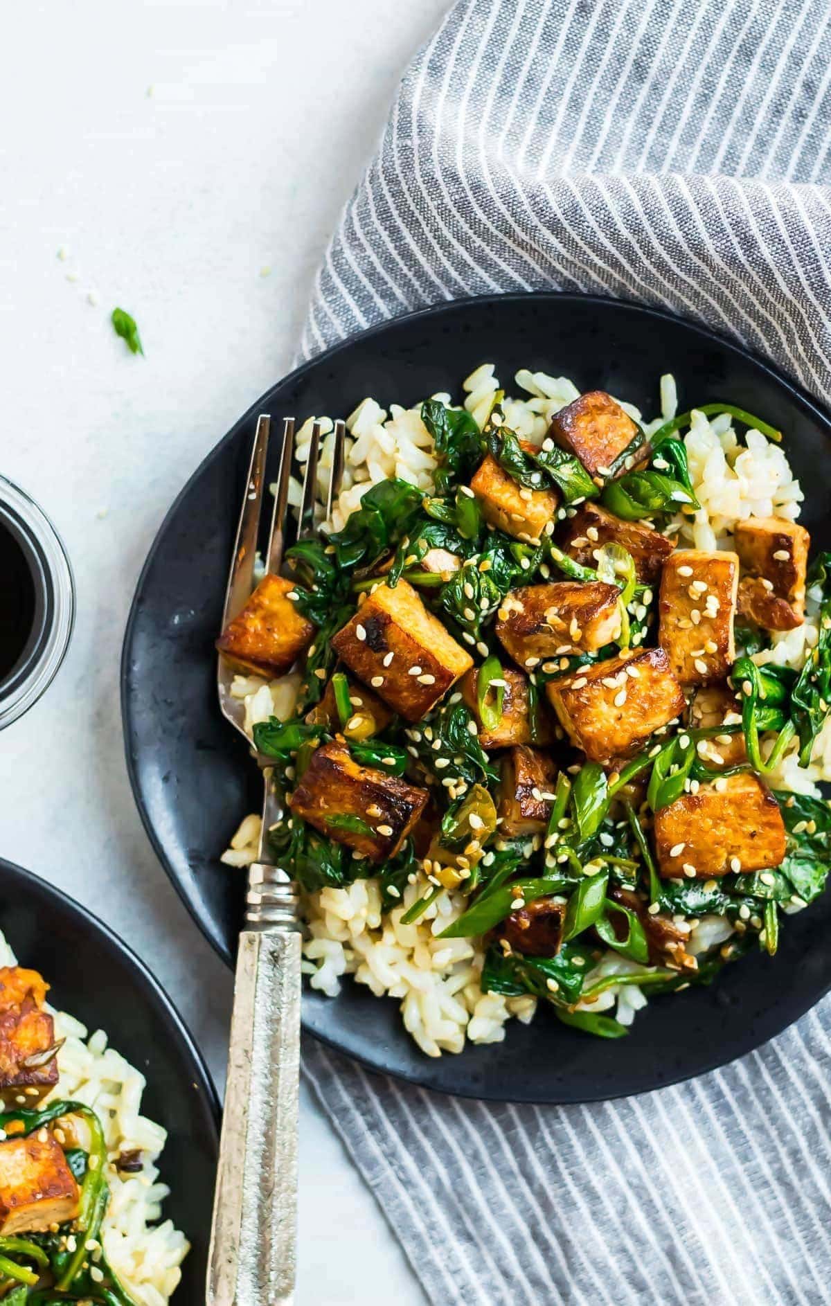 Rice topped with stir fry tofu sprinkled with sesame seeds. 