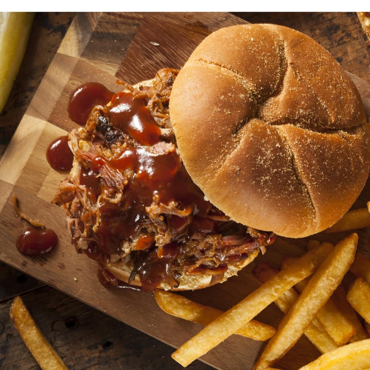 Top view of Dr. Pepper Pulled Pork with fries on a wooden cutting board
