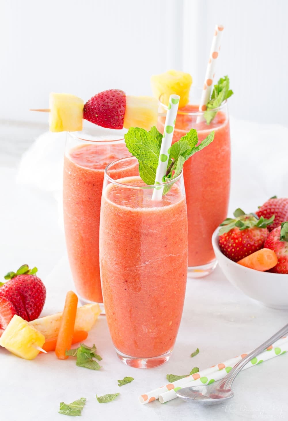 Three tall glasses of Tropical Carrot Smoothie with carrots, strawberries, mango and pineapple chunks