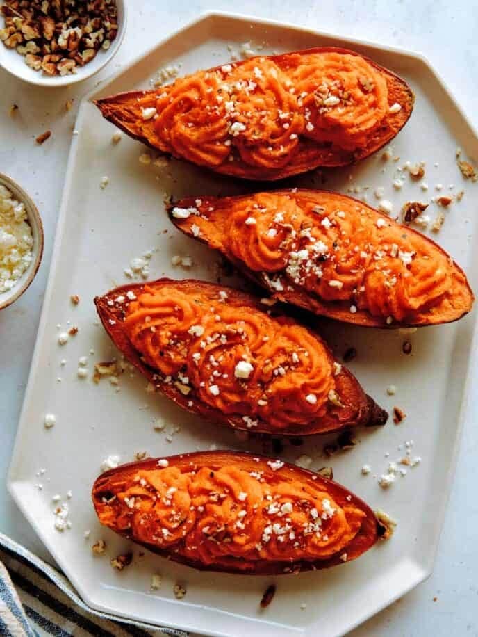 baked sweet potatoes sliced in half with creamy filling and garnished with cheese. 