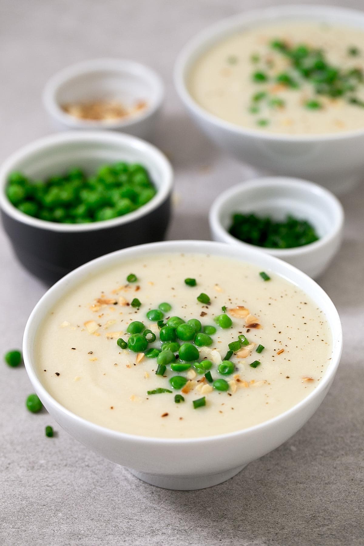 Bowls of homemade Vegan Cauliflower Soup with green peas on top