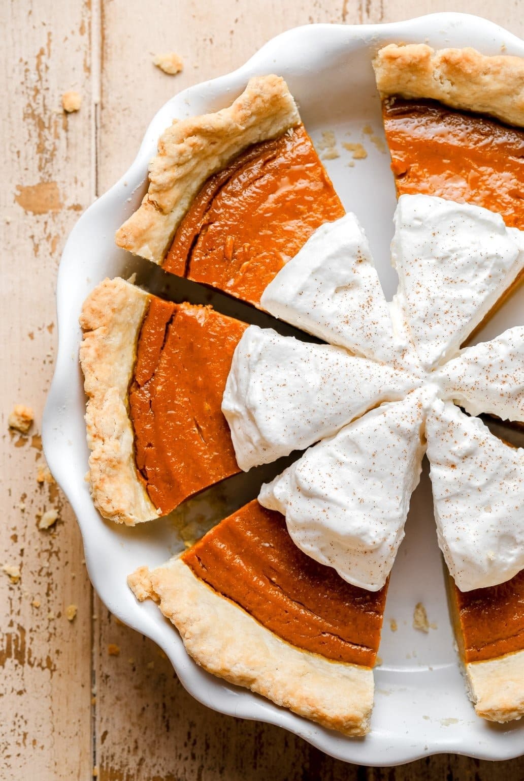 Sliced whole pumpkin pie with whipped cream. 