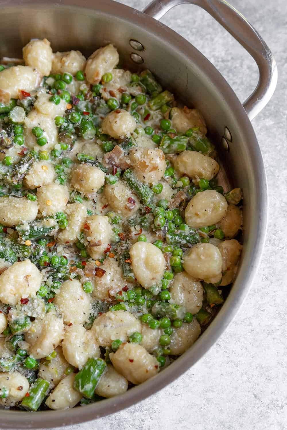 Spring vegetable gnocchi cooked on a pot with peas and cheese. 