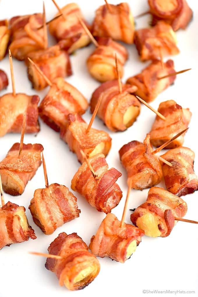 Pineapple chunks wrapped with bacon strips and sealed with a stick. 