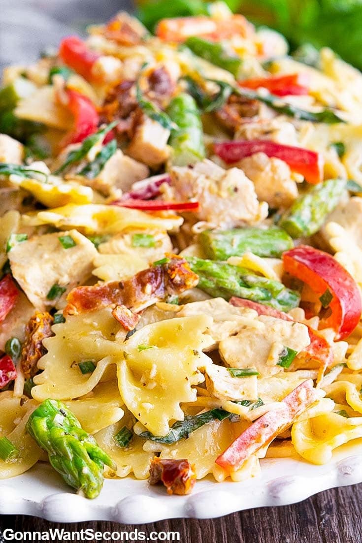 Chicken pasta salad served on a white plate made with veggies, pasta and creamy dressing. 