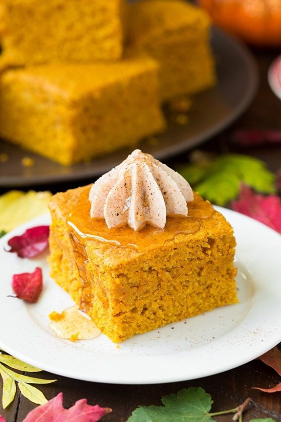A slice of pumpkin cornbread on a plate topped with honey cinnamon butter.