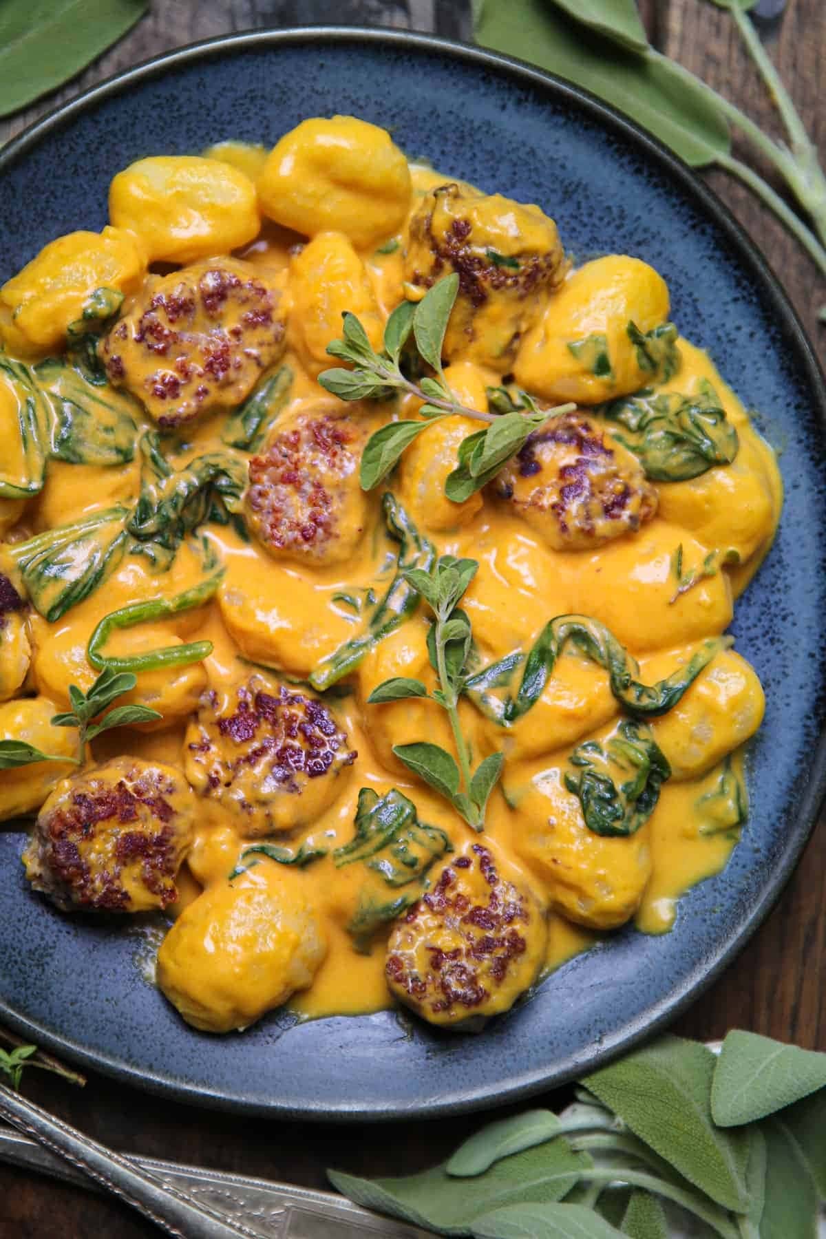 Creamy pumpkin gnocchi with spinach and Italian sausage on a plate. 