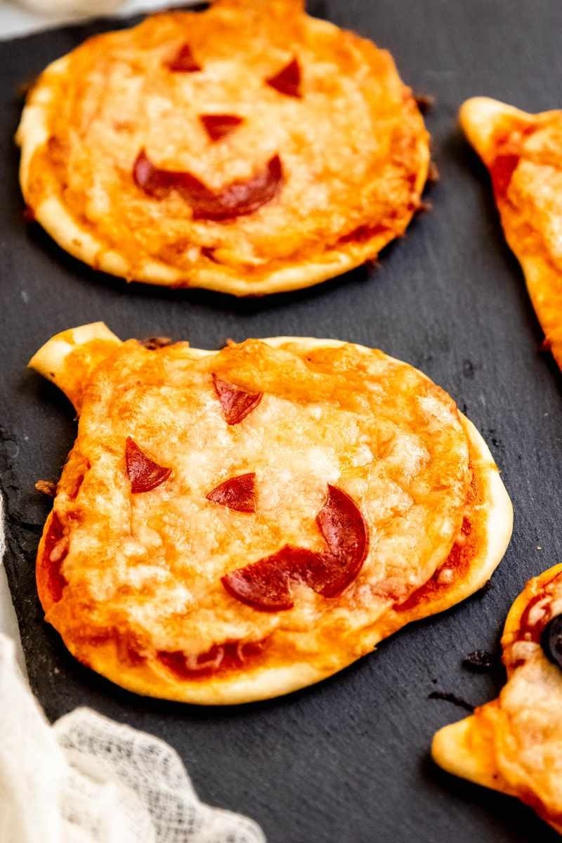 Mini Halloween-shaped pizzas on a concrete surface. 