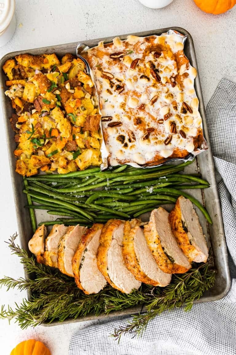Sliced turkey breast, stuffing, sweet potato casserole, and green beans on a sheet pan.