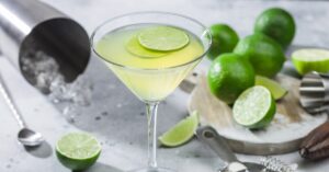 A martini glass with lime slices on the side