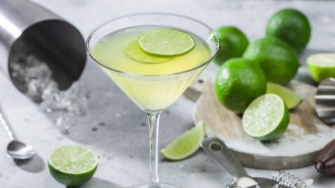 A martini glass with lime slices on the side