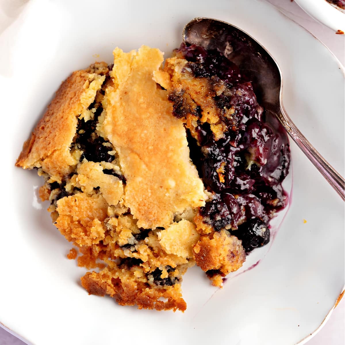 Blueberry dump cake with a spoon, a delicious dessert with a golden crust