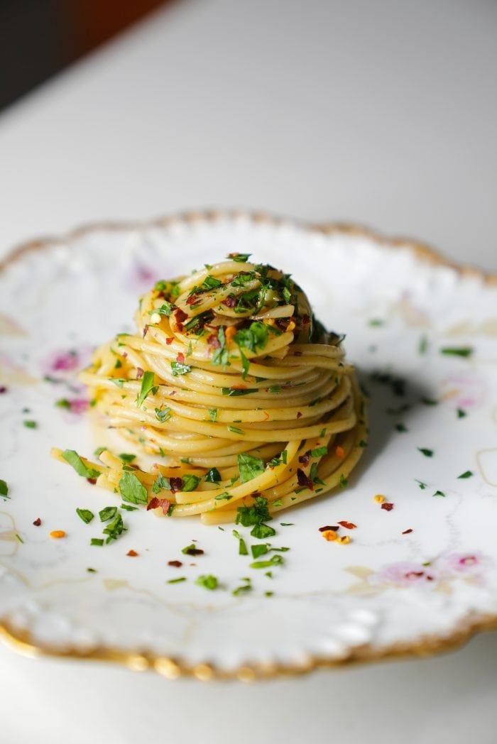 A serving of spaghetti olio garnished with herbs. 