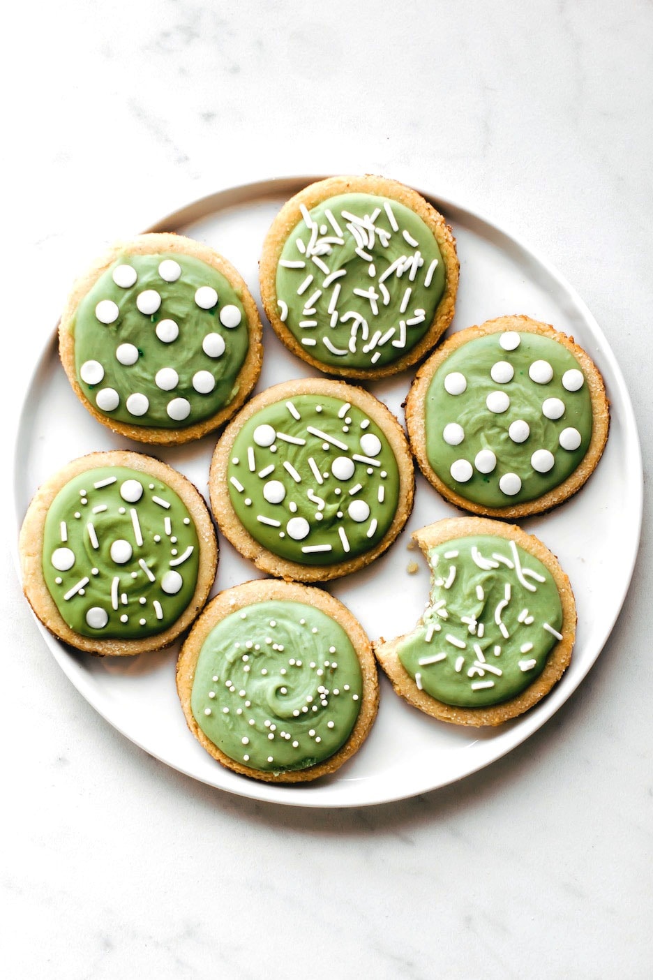 Sugar cookies with green  frosting on top. 